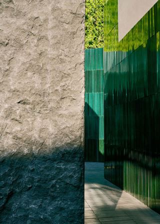 Zona di lusso decorata con piastrelle in pietra lavica verde e parete in pietra grezza.
